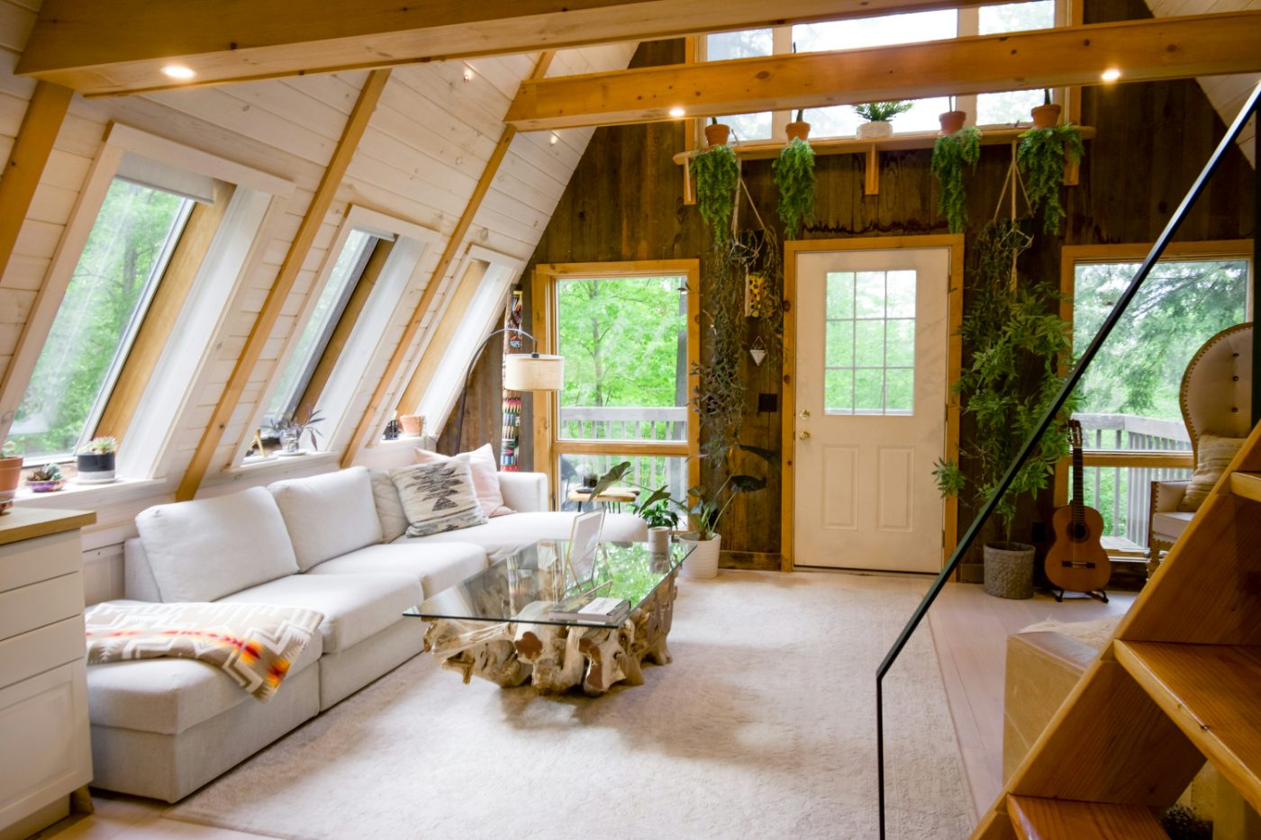 An A-frame cabin living room with a white sofa and forest views.
